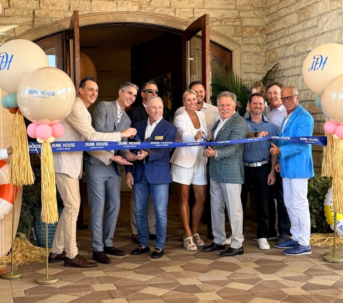 group of 11 people standing conducting a ribbon cutting at the dune house hotel and spa in atlantic beach